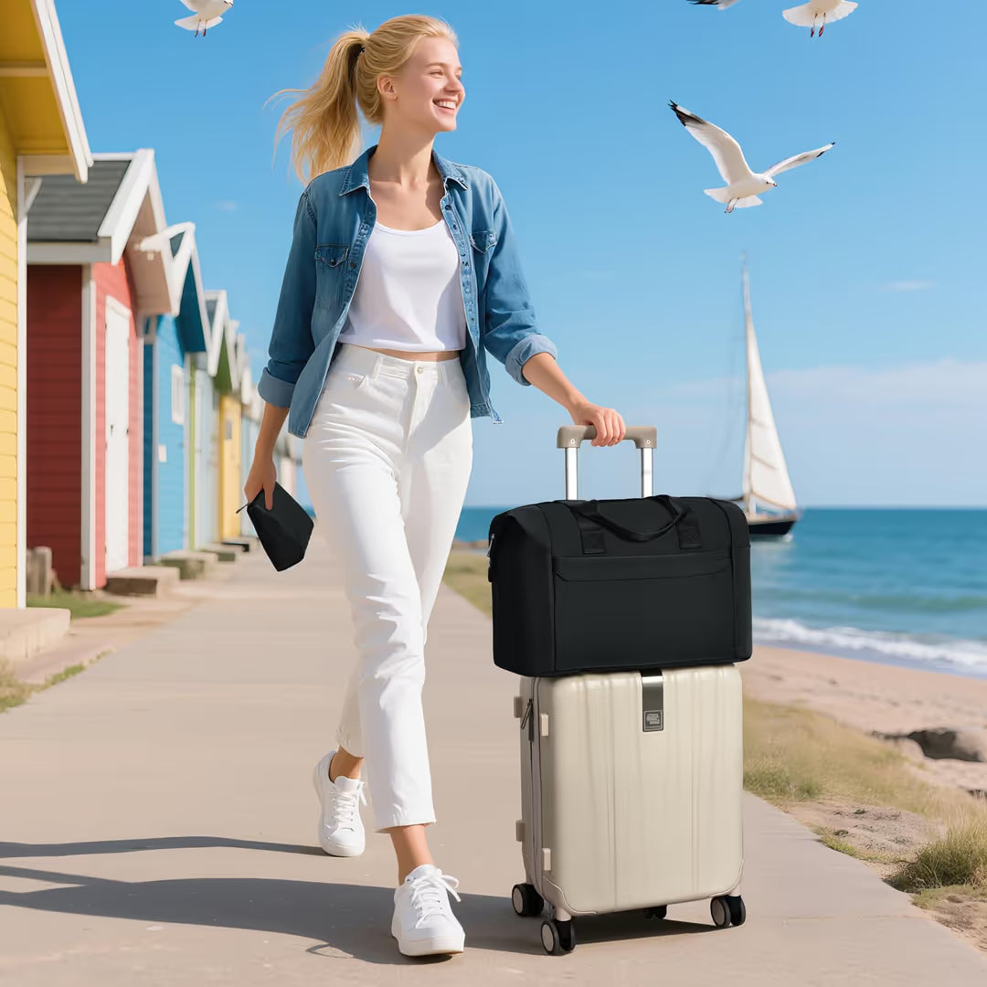 Woman walking with a suitcase and black bag near colorful houses and the ocean.