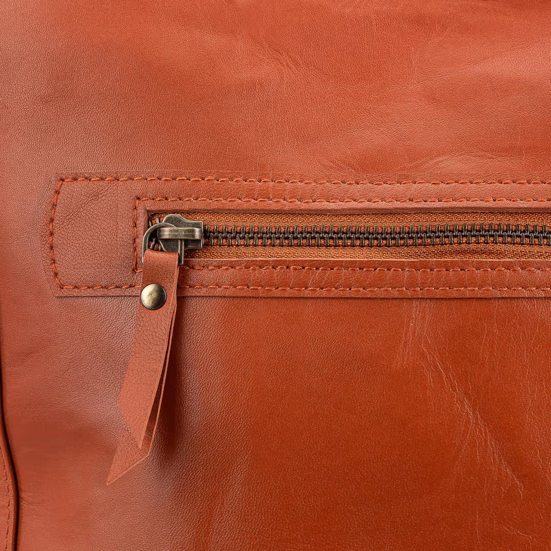 Close-up of a brown leather bag with a zipper