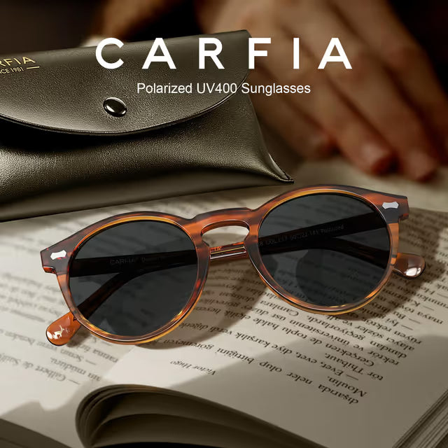 Brown sunglasses with dark lenses on an open book, with 'CARFIA' branding.