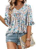 Woman wearing a floral blouse and denim shorts, holding a straw bag.