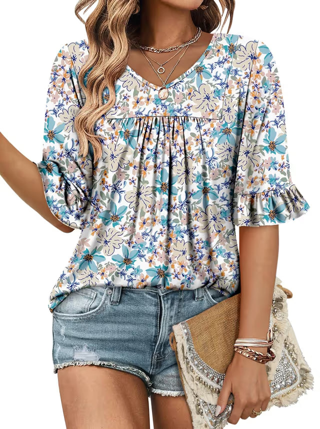 Woman wearing a floral blouse and denim shorts, holding a straw bag.