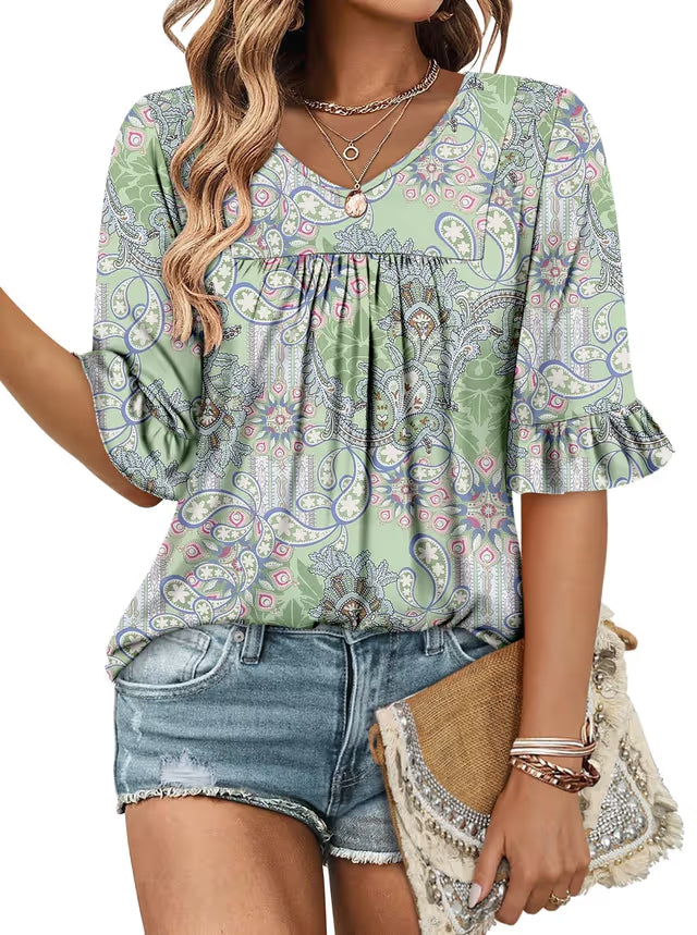 Woman wearing a patterned blouse and denim shorts, holding a straw bag.