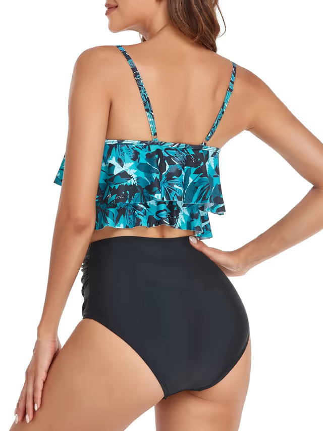 Woman wearing a blue floral top and black high-waisted bikini bottom on a white background